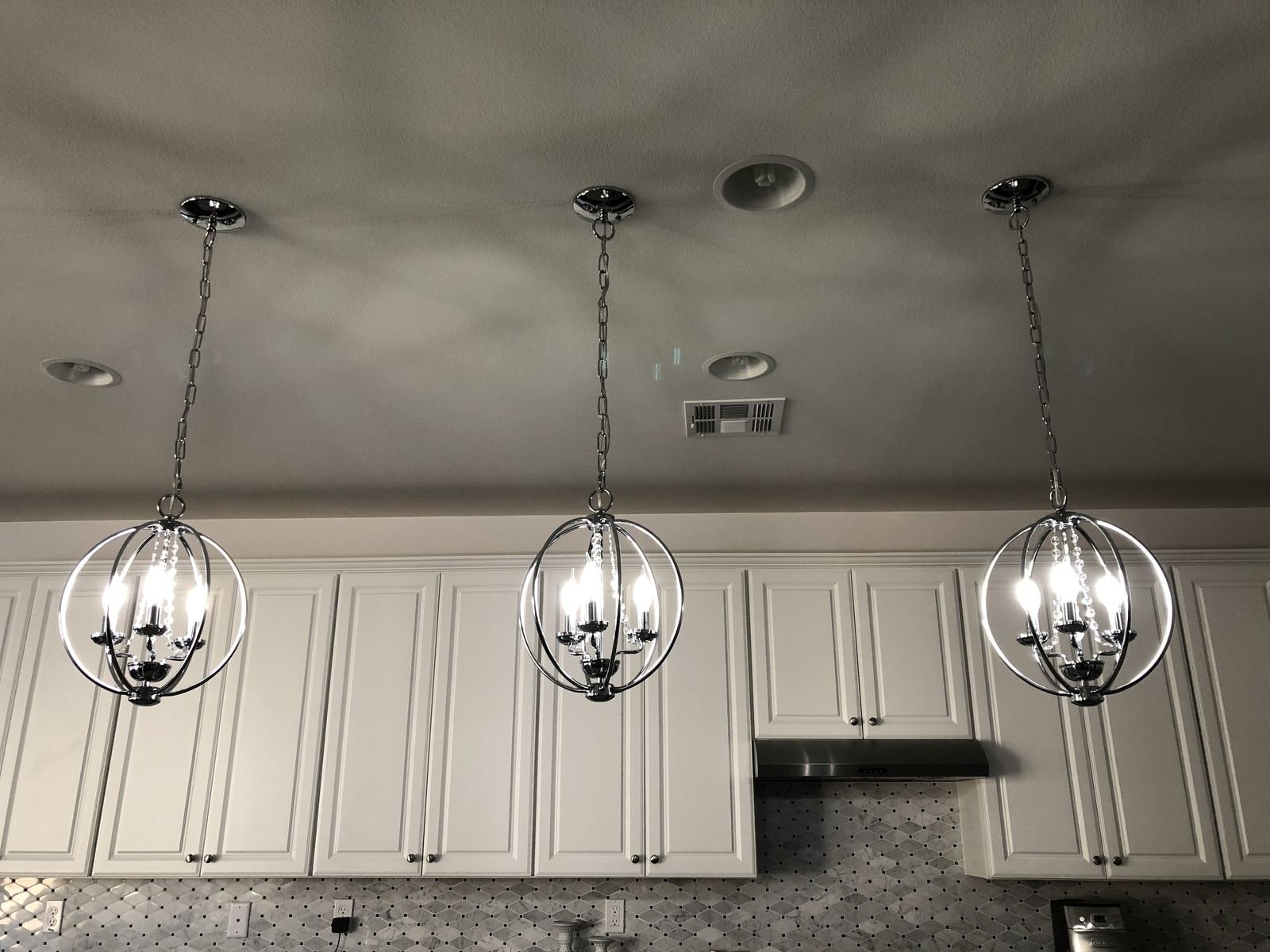 Custom chrome orb chandelier installation over kitchen island